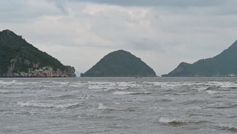 Se-Ve-Un-Barco-Navegando-Hacia-La-Izquierda-Mientras-Tres-Islas-En-El-Horizonte-Completan-La-Imagen-De-Un-Mar-Agitado,-Parque-Nacional-Khao-Sam-Roi-Yot,-Phrahuap-Khiri-Khan,-Tailandia