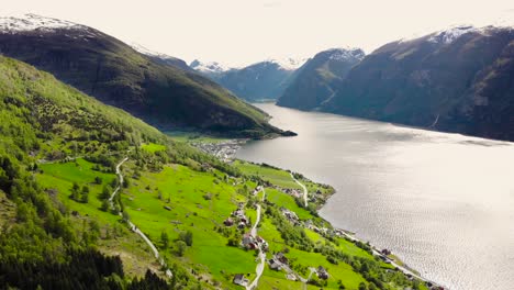Aerial:-flying-above-the-sognefjord-from-a-mountainside-and-a-town-in-the-background
