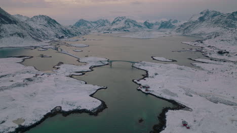 Aerial-view-over-Ramberg-village-Nordland-frozen-ice-fjord-lake-and-panoramic-mountains,-Scandinavia