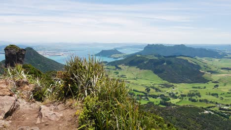 Aerial-panorama-shot-from-viewpoint-over-beautiful-mountain-landscape-and-ocean-during-sunny-day---Te-Whara-Track,New-Zealand