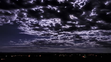 Dramatic-night-timelapse-of-cloud-passing-over-head-at-night-and-reflecting-the-moon-light-over-Moroccan-city