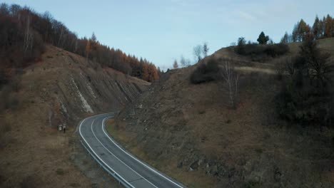 An-aerial-drone-view-of-car-driving-on-a-winding-road-running-through-a-canyon-in-late-autumn