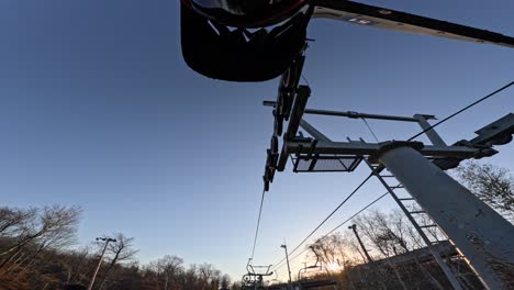 mtb-rider-looks-and-waves-at-camera-on-chairlift-going-up-mountain-sunset