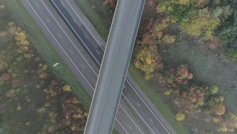 Overhead-drone-shots-of-mountainbiker-riding-over-overpass-of-the-highway-and-nature