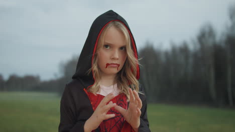 Porträt-Eines-Kaukasischen-Jungen-Mädchens-An-Halloween,-Gekleidet-In-Einem-Vampirkostüm,-Wald-Im-Hintergrund
