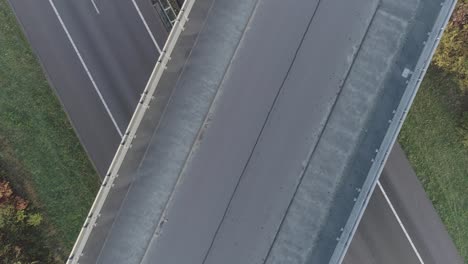 Above-drone-shot-of-big-road-and-highway-crossing,-mountainbiker-crossing-underneath