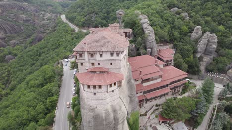 Aerial-circular-view-over-magnificent-monastery-and-a-road-with-passing-cars