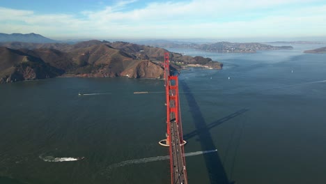 Aerial-view-overlooking-car-and-boat-traffic-at-the-Golden-gate-bridge,-in-sunny-California---circling,-drone-shot