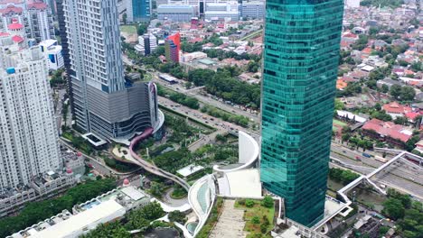 Hohe-Hochhäuser-Und-Einkaufszentrum-In-Der-Nähe-Der-Autobahn-Mit-Fahrzeugen-In-West-Jakarta