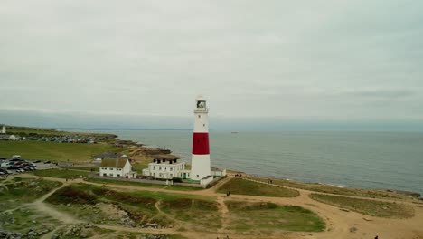 Red-and-white-lighthouse-of-Portland,-UK,-drone-fly-away-shot