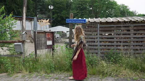 Female-Eco-Conscious-Hippie-Showing-Sign-Post-To-Sustainable-Village-Living
