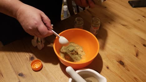 Female-measures-Moringa-turmeric-and-ginger-powder-herbal-remedy-supplement-in-kitchen-bowl