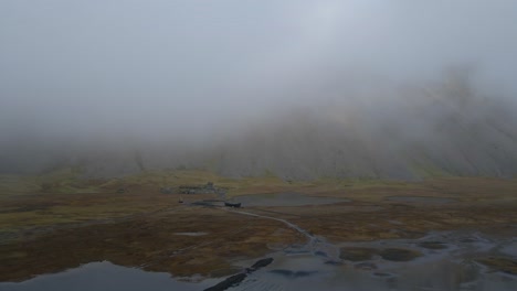 Viking-village-reconstruction-with-Vestrahorn-mountain-shrouded-in-fog,-Stokknes-peninsula-in-Iceland
