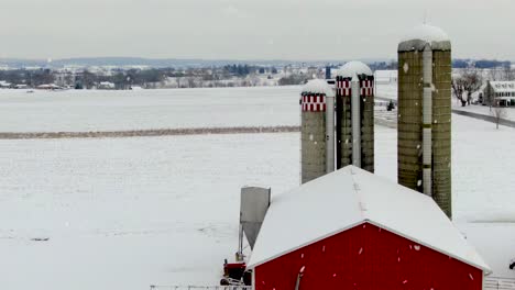 Rückantenne-Zeigt-Rote-Scheunen-Und-Farm-Während-Des-Winterschneesturms