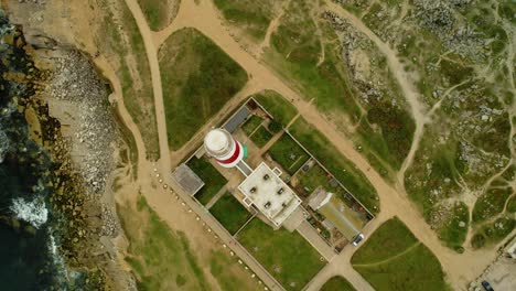 Coastal-lighthouse-building-complex,-aerial-top-down-descending-view