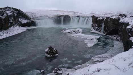 Luftaufnahme-Des-Godafoss-Wasserfalls,-Der-Im-Winter-In-Den-Skjalfandafljot-Fluss-Auf-Der-Nordinsel-Fließt---Eisfluss-Und-Eisberg,-Der-Auf-Der-Wasseroberfläche-Schwimmt