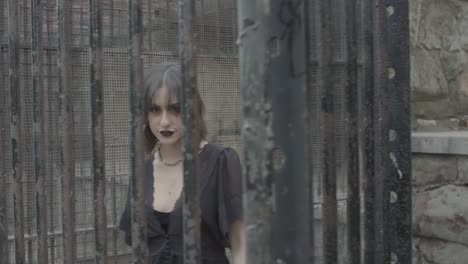 Slow-motion-shot-of-a-goth-girl-behind-rusted-animal-cage-bars