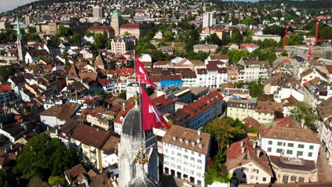 Beautiful-and-interesting-rotating-drone-shot-showing-the-Grossmunster-church-in-Zürich,-Switzerland-and-its-surroundings-in-the-background