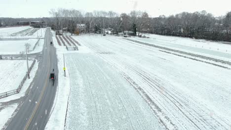 Aerial-of-Amish-horse-and-buggy-on-road-in-Lancaster-County-Pennsylvania-during-winter-snowstorm