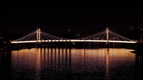 Albert-Bridge,-London,-illuminated-at-night-and-reflected-in-the-River-Thames