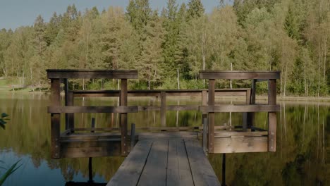 Wooden-Bridge-At-Kypesjön-Lake-in-Borås,-Sweden-at-Late-Summer-Afternoon---Wide-Shot-Tracking-Forward-and-Turning-Left