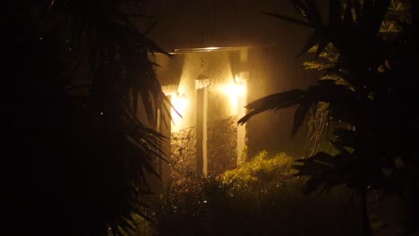 Two-incandescent-lightbulbs-light-up-rural-building-during-a-tropical-rain-storm-in-Hawaii