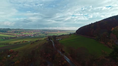 Drone-Volando-Sobre-Hermosos-Paisajes-De-Alemania-Con-Turbinas-De-Viento-En-La-Distancia