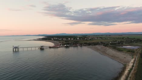Aerial-view-of-fishing-huts-on-shores-of-estuary-at-sunset,italian-fishing-machine,-called-""trabucco"",Lido-di-Dante,-Ravenna-near-Comacchio-valley