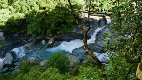 Kleine-Wasserfallkaskade,-Die-Die-Bewachsenen-Berge-Neuseelands-Hinunterfließt,-Während-Die-Sonne---Raub-Roy-Gletscher,-Neuseeland