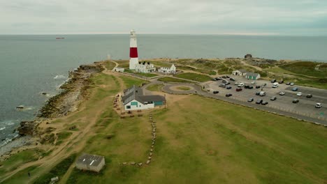 Portland-Bill-Lighthouse-beacon-on-Jurassic-coast-cliffs-aerial-view-dolly-right