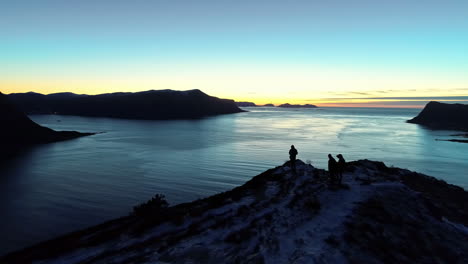 Silhouette-of-unrecognizable-people-admiring-sunset-on-Alesund-fjord-In-Norway