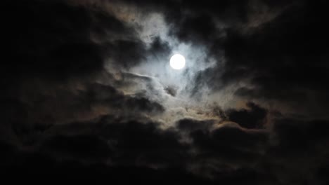 Slow-time-lapse-of-stationary-full-moon-with-halo-behind-clouds,-copy-space
