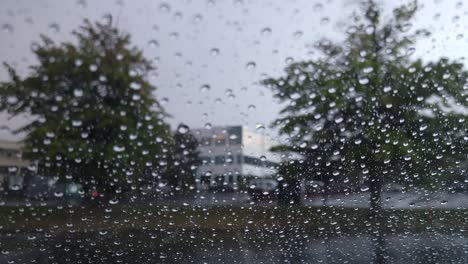Shot-from-inside-a-car-of-wet-car-glass-window-during-rain-while-parked-in-a-parking-lot-on-a-rainy-day