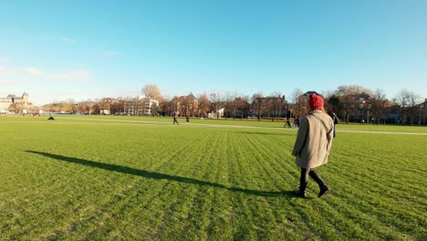 Carefree-girl-walking-alone-in-a-green-grass-field-and-park-on-sunny-winter-day