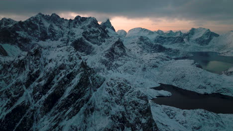 Frozen-alien-Lofoten-Svartvatnet-head-jagged-mountain-range-terrain-aerial-view-flying-towards-ghostly-cold-valley