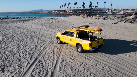 Aerial-view-of-Oceanside-lifeguard-truck-driving-down-the-beach