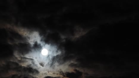 Slow-timelapse-of-rising-full-moon-behind-broken-clouds,-copy-space