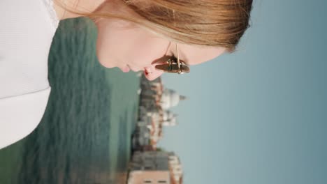 Vertikale-Aufnahme-Einer-Blonden-Touristin-Mit-Geflochtenem-Haar-Und-Sonnenbrille,-Die-An-Berühmten-Schauplätzen-Entlang-Des-Grand-Canal-In-Venedig,-Italien,-Zuschaut