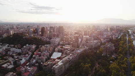 Glowing-sunrise-over-Santiago-Chile-vast-cityscape-metropolis-with-Andes-mountain-range-on-the-skyline-Aerial-orbiting-view