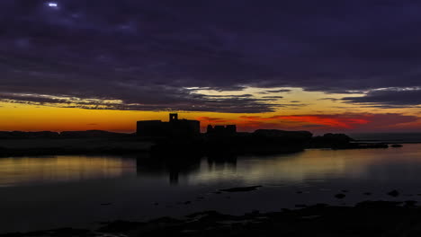 Zeitraffer-Bei-Einem-Wunderschönen-Orangefarbenen-Sonnenuntergang-Am-Rande-Eines-Sees-Mit-Silhouetten-Von-Gebäuden-Im-Hintergrund