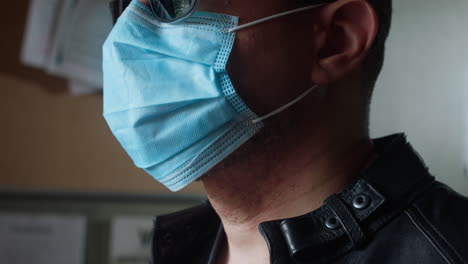 Man-wearing-a-covid-19-type-of-surgical-mask-is-standing-inside