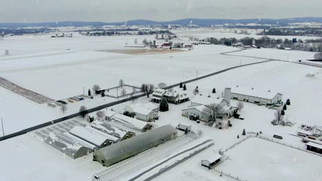 Aerial-orbit-of-American-farm-and-greenhouse-buildings-covered-in-winter-snow