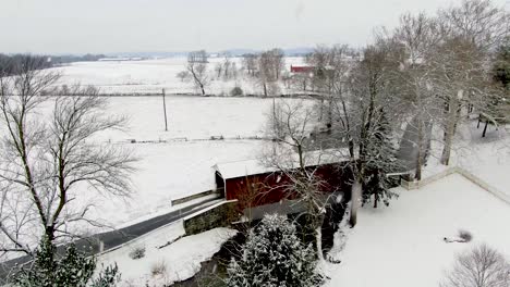 Aerial-of-red-covered-bridge-over-water-in-stream
