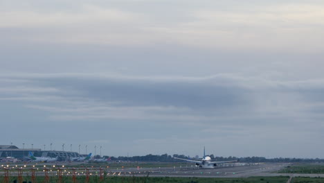 Back-telephoto-view-of-standard-commercial-plane-touching-ground-in-landing-lane