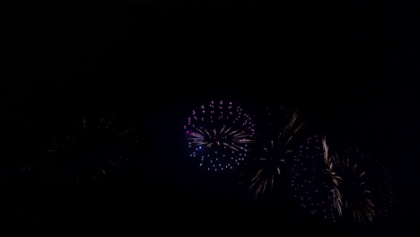 Colorful-blue-and-purple-fireworks-bursting-against-the-black-sky,-2022-New-year-celebration-copy-space