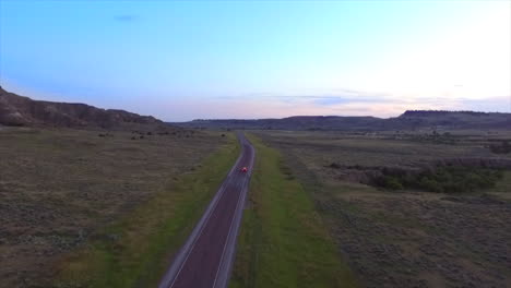 Eine-Filmische-Drohnenaufnahme-Eines-Autos,-Das-Irgendwo-Mitten-In-Wyoming-Einen-Highway-Hinunterfährt