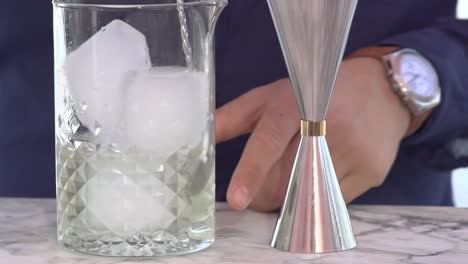 professional-barman-mixing-a-cocktail-with-ice-and-alcohol-outside-bar,-close-up-slow-motion