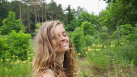 Slow-motion-close-up-of-a-happy-tousled-blonde-hippie-caucasian-girl-walking-on-a-rural-campsite-in-nature