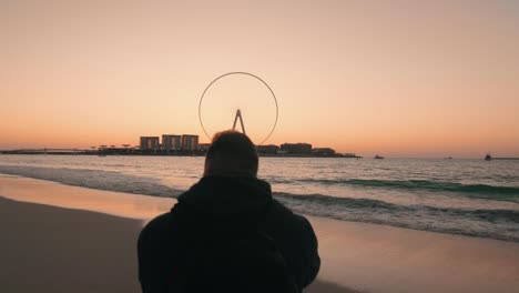 Man-Take-Photo-Of-Seascape-with-Ferris-wheel-at-Sunset