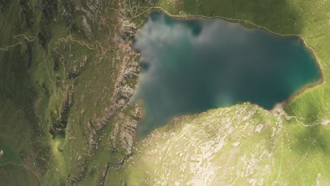 Aerial-overhead-reveal-shot-of-mountain-lake-Lago-Grande-on-a-sunny-day